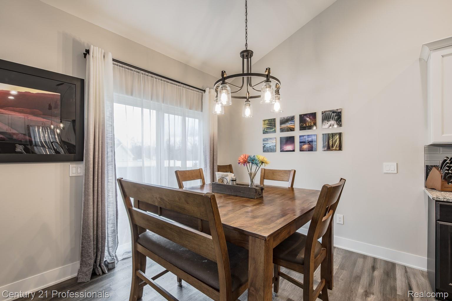 4914 TORATOLA Lane Howell, MI 48843 - Photo 13 of 39 Dining area featuring lofted ceiling, a chandelier, and dark wood-style floors