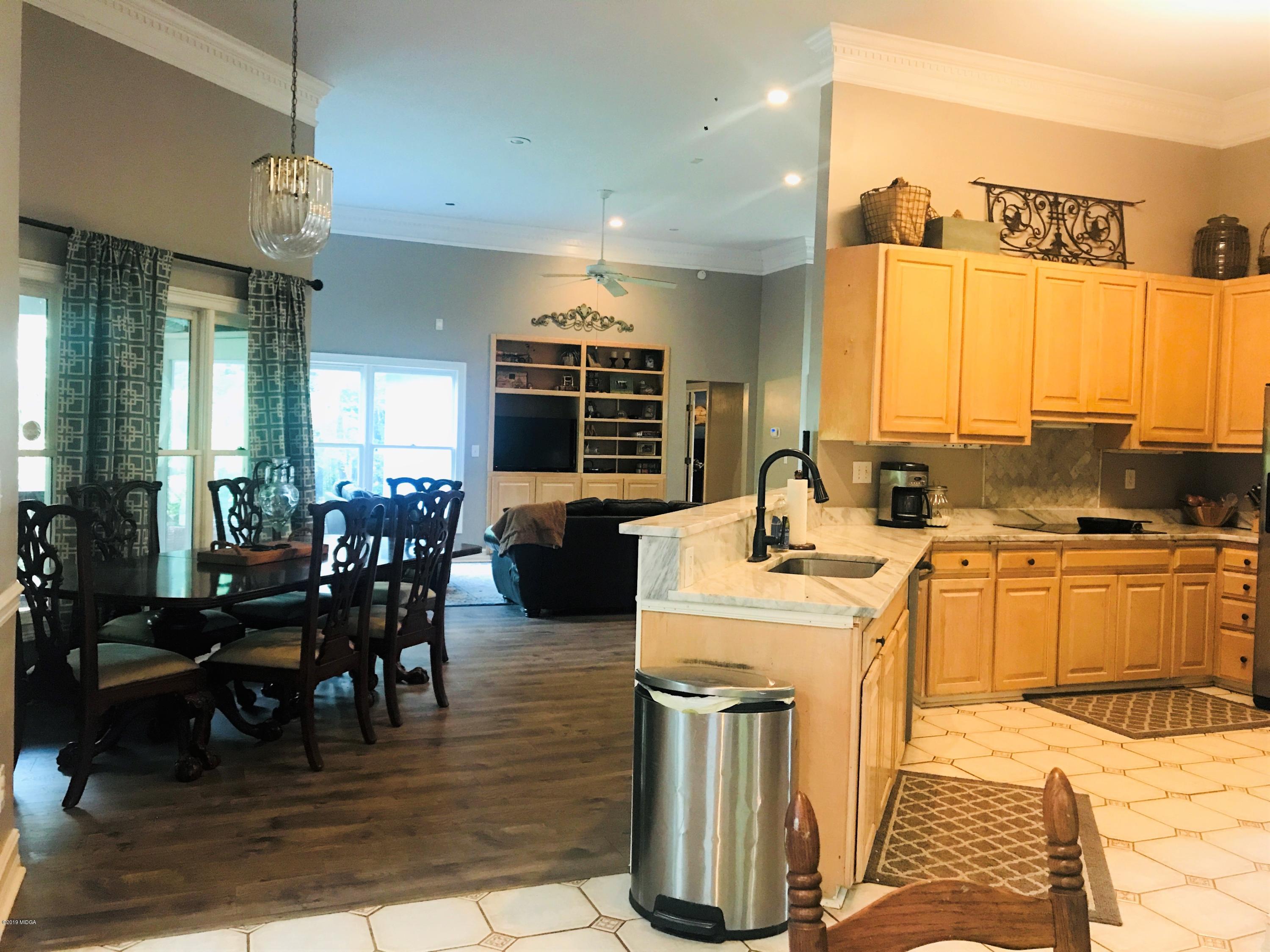 1569 Johnson Road Macon, GA 31220 - Photo 25 of 28 a open kitchen with stainless steel appliances kitchen island granite countertop a sink dishwasher a dining table and chairs with wooden floor