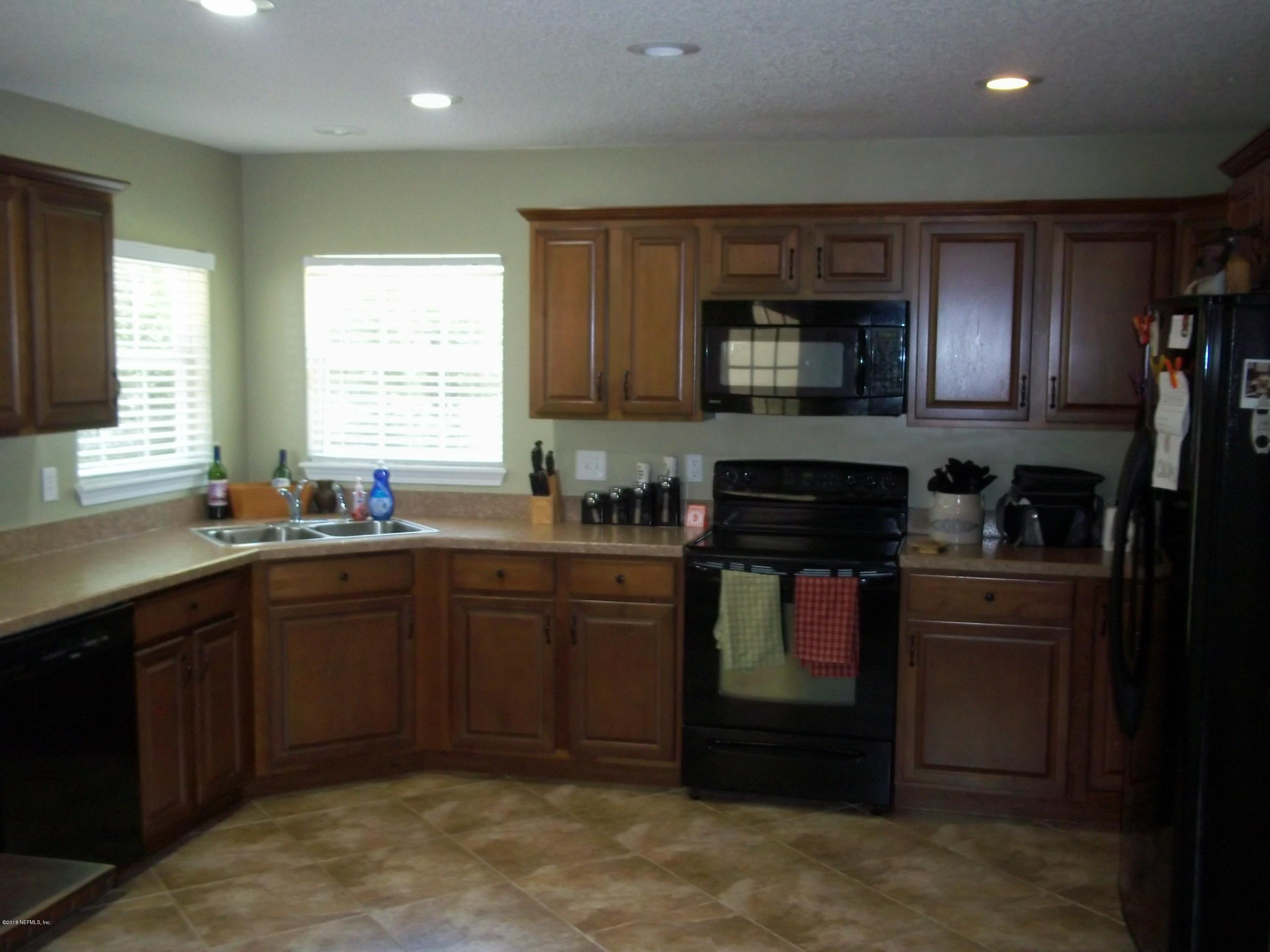5579 Long Branch Road Jacksonville, FL 32234 - Photo 20 of 54 a kitchen with stainless steel appliances granite countertop wooden cabinets stove top oven and sink