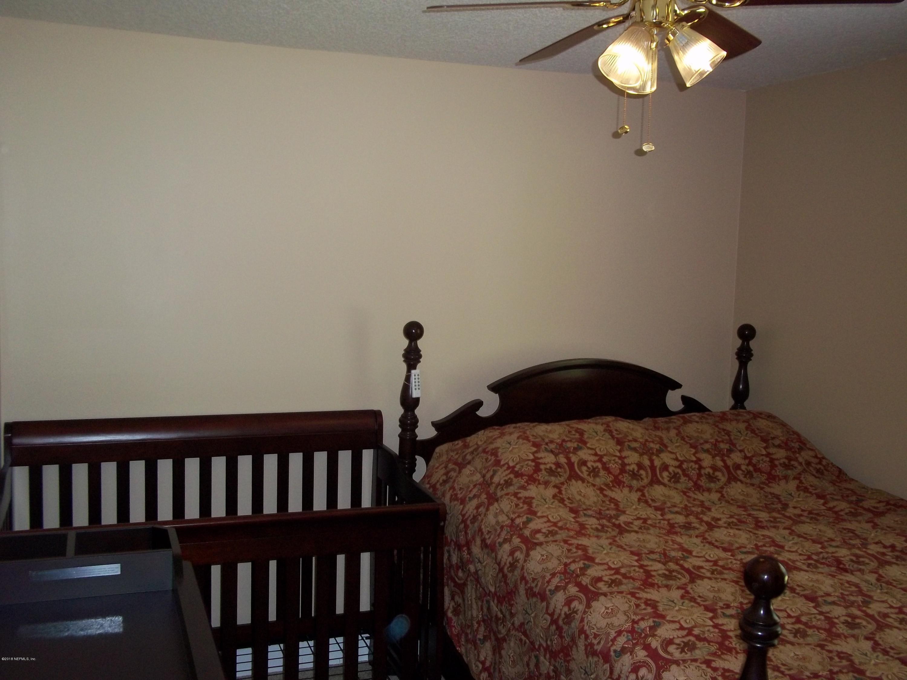 5579 Long Branch Road Jacksonville, FL 32234 - Photo 27 of 54 a bedroom with a bed and chandelier
