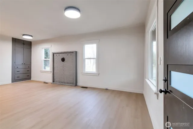 an empty room with wooden floor and windows