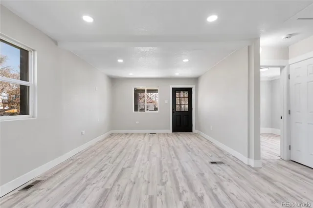 an empty room with wooden floor and windows