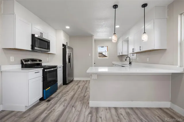 a kitchen with stainless steel appliances a sink a stove a refrigerator and cabinets