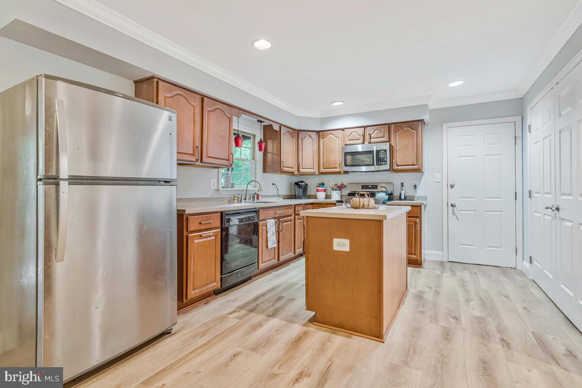 5963 Hillside Road St. Leonard, MD 20685 - Photo 18 of 54 a kitchen with stainless steel appliances granite countertop a refrigerator a sink a stove and white cabinets with wooden floor