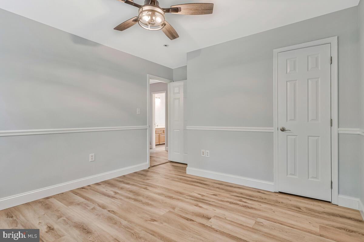5963 Hillside Road St. Leonard, MD 20685 - Photo 35 of 54 an empty room with wooden floor fan and windows
