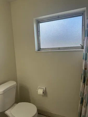 a white toilet sitting next to a small window
