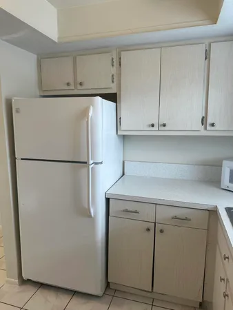 a view of a kitchen with white cabinets and a refrigerator