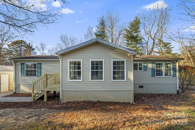 a view of a house with a yard chairs and wooden fence
