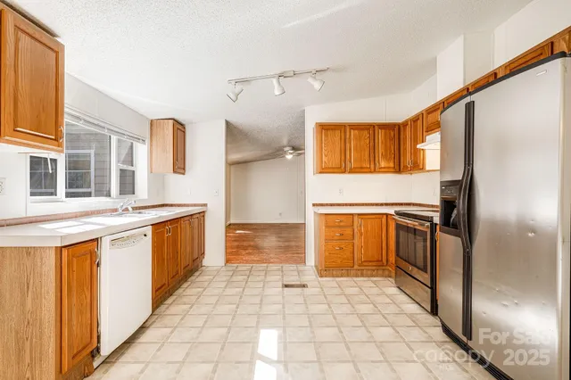 a kitchen with granite countertop a refrigerator a stove and white cabinets with wooden floor