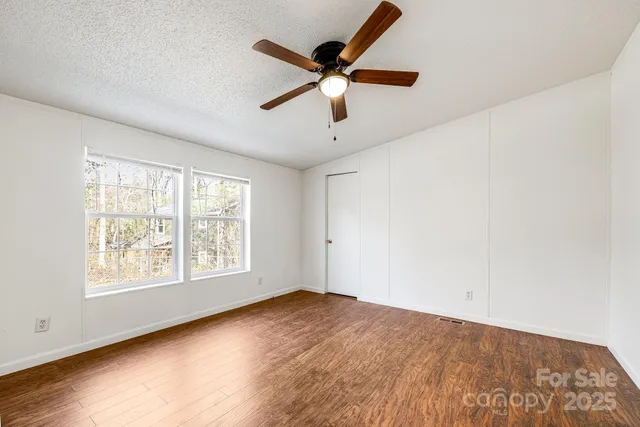 a view of empty room with wooden floor and ceiling fan