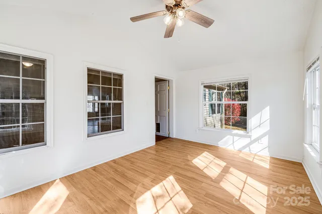 a view of an empty room with a window and wooden floor