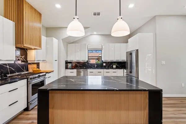 a large kitchen with granite countertop a stove a sink a center island and cabinets