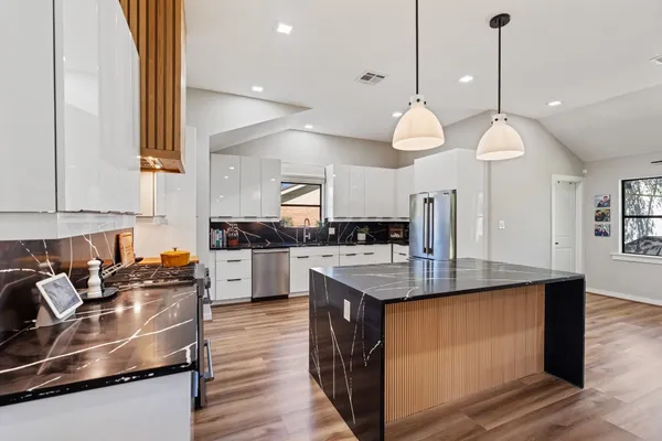 a kitchen with stainless steel appliances granite countertop a sink a stove and a wooden floor