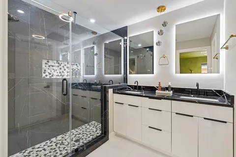 a bathroom with a granite countertop sink a mirror a vanity and shower