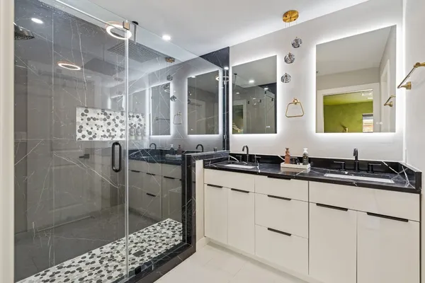 a bathroom with a granite countertop sink a mirror a vanity and shower
