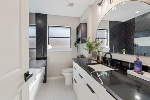a spacious bathroom with a granite countertop sink a toilet a mirror and shower
