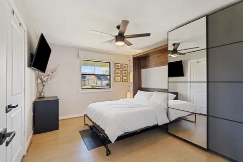 a bedroom with a bed a flat screen tv and a ceiling fan