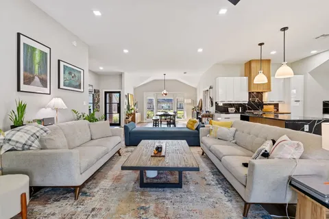 a living room with furniture kitchen view and a chandelier