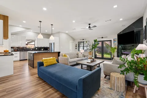 a living room with furniture kitchen view and a large window
