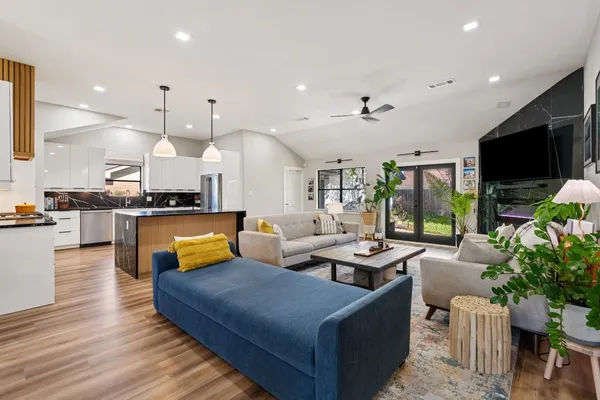 a living room with furniture kitchen view and a large window