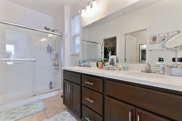a bathroom with a double vanity sink mirror and shower