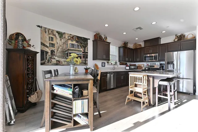 a kitchen with stainless steel appliances granite countertop a refrigerator a sink dishwasher a stove and white cabinets with wooden floor