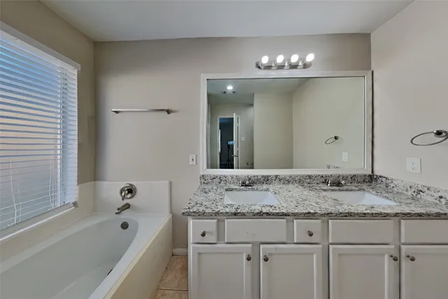 a bathroom with a granite countertop sink tub and mirror