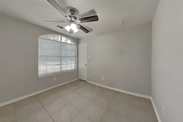 en empty room with windows and chandelier fan