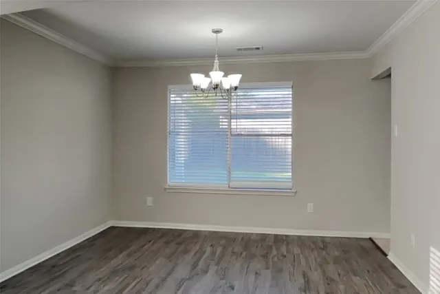 an empty room with wooden floor chandelier and window