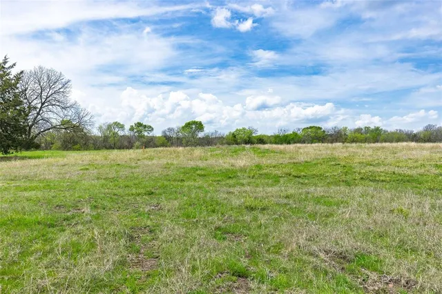a view of a green field with wooden fence