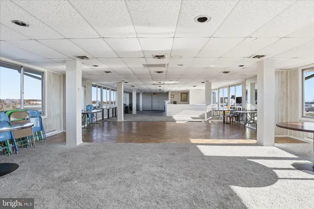 a view of a livingroom with dining area a chandelier fan and windows