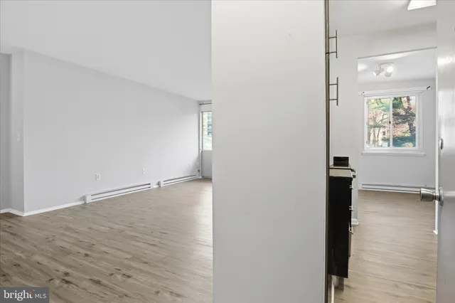 a view of an empty room with wooden floor and a window