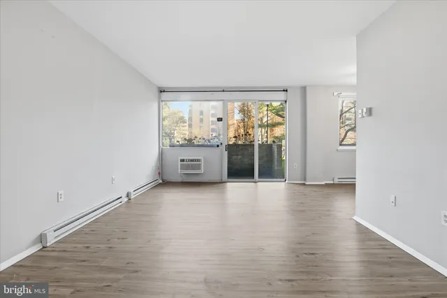 a view of an empty room with wooden floor and a window