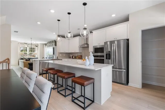 a kitchen with stainless steel appliances kitchen island a refrigerator and chairs