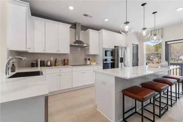 a kitchen with stainless steel appliances kitchen island granite countertop a table chairs sink and cabinets