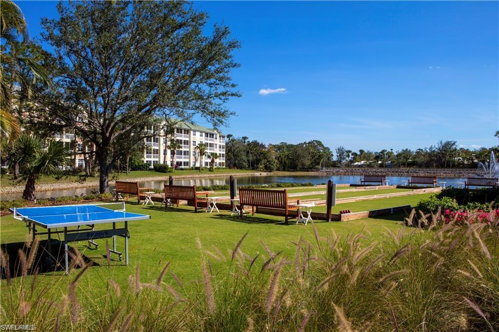 106 Cypress View Drive, Unit C8 Naples, FL 34113 - Photo 26 of 30 a view of a swimming pool with lawn chairs under an umbrella