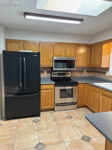 a kitchen with granite countertop a refrigerator and a stove top oven