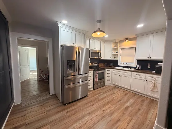 a kitchen with a refrigerator cabinets and wooden floor