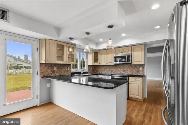 a large kitchen with stainless steel appliances granite countertop a refrigerator a stove a sink and a granite countertops with wooden floor