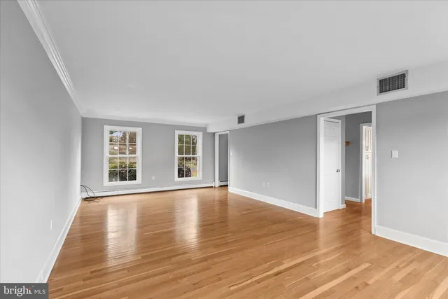a view of an empty room with wooden floor and windows
