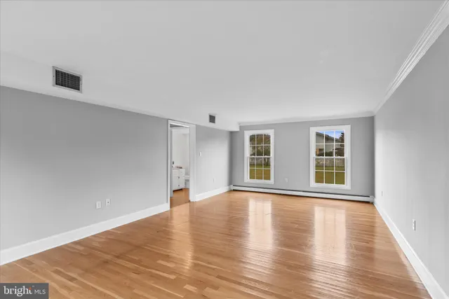 a view of an empty room with a window and wooden floor