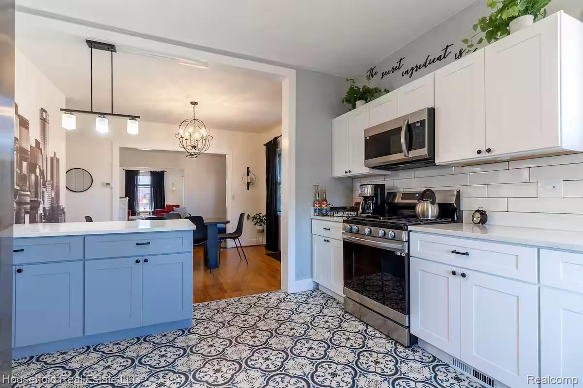 4446 Commonwealth Street Detroit, MI 48208 - Photo 19 of 28 Kitchen with stainless steel appliances, a peninsula, tasteful backsplash, hanging lights, and white cabinetry