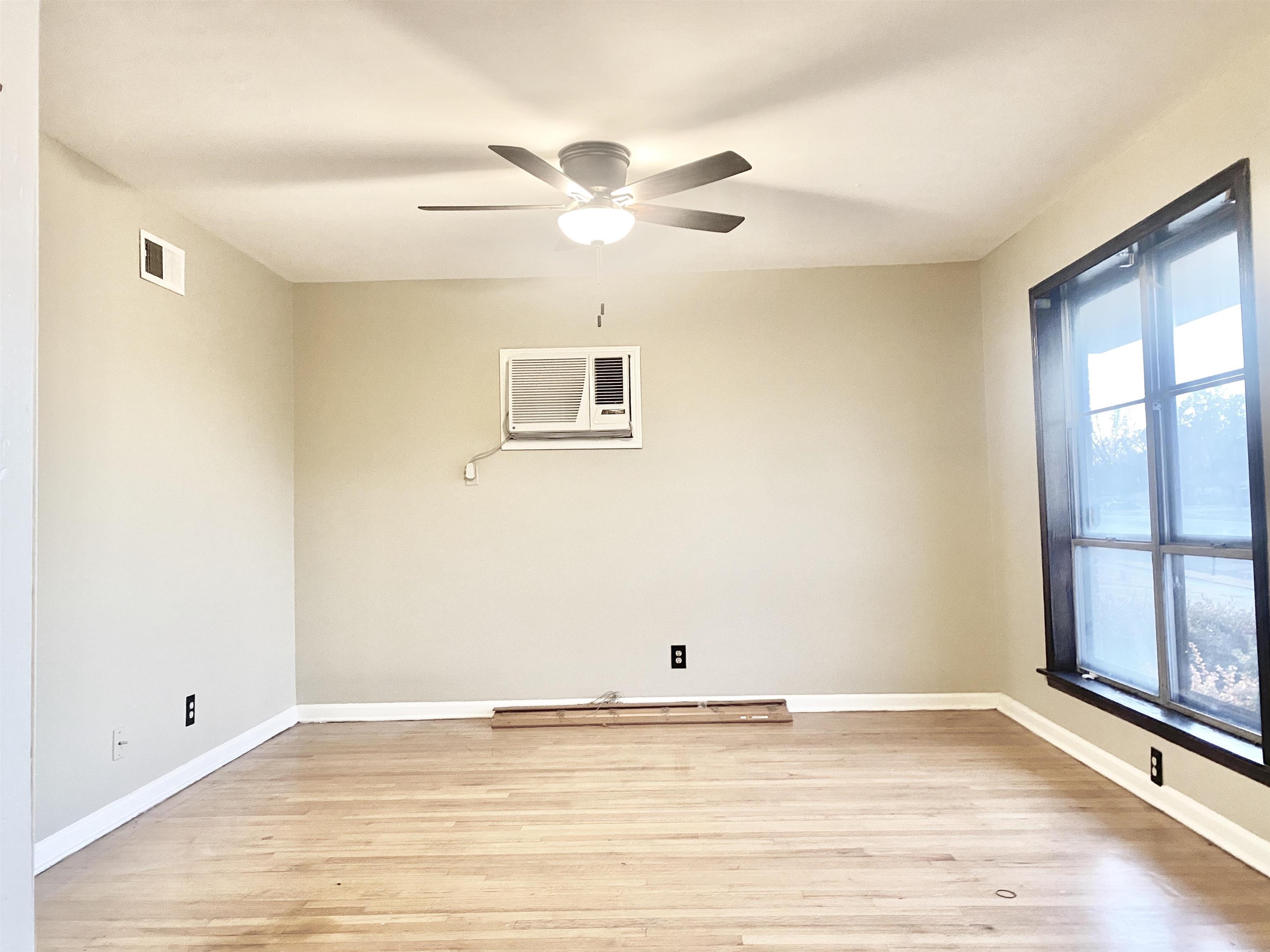 3536 West Horn Lake Road Memphis, TN 38109 - Photo 5 of 12 a view of an empty room with window and wooden floor