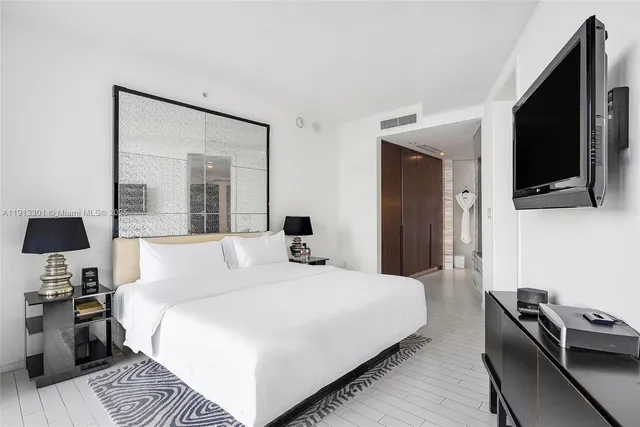 a bedroom with a bed and a flat tv screen on a dresser