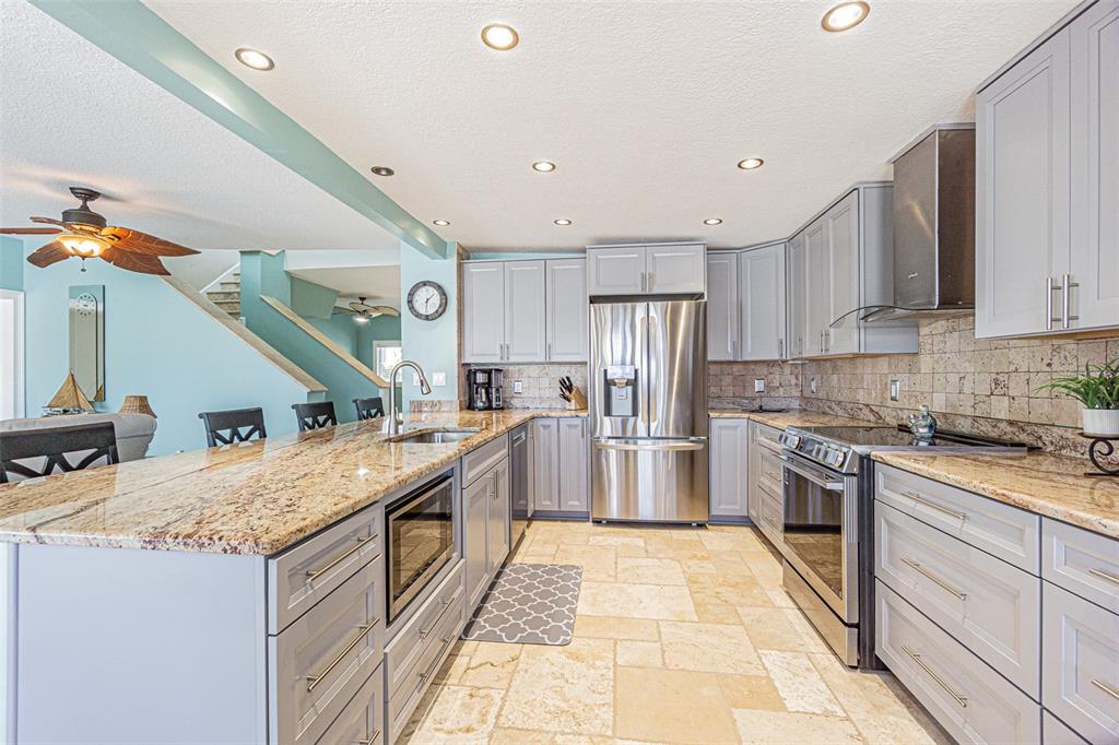 121 Wall Street Redington Shores, FL 33708 - Photo 2 of 38 a large kitchen with stainless steel appliances granite countertop a sink and dishwasher a stove with wooden floor