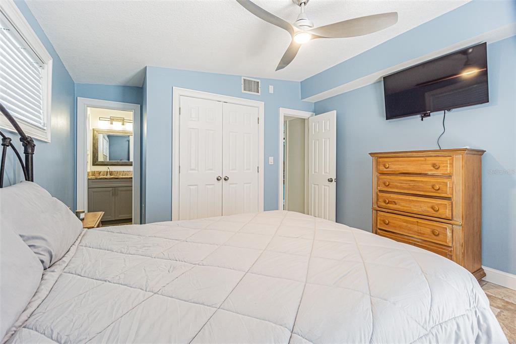 121 Wall Street Redington Shores, FL 33708 - Photo 10 of 38 a bedroom with a bed a flat screen tv and a chandelier
