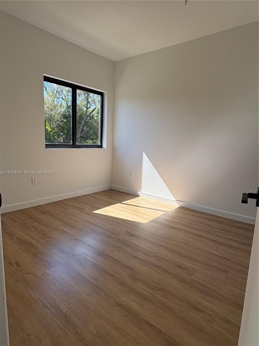 85 Northeast 55th Street, Unit 3 Miami, FL 33137 - Photo 10 of 15 a view of empty room with wooden floor and fan