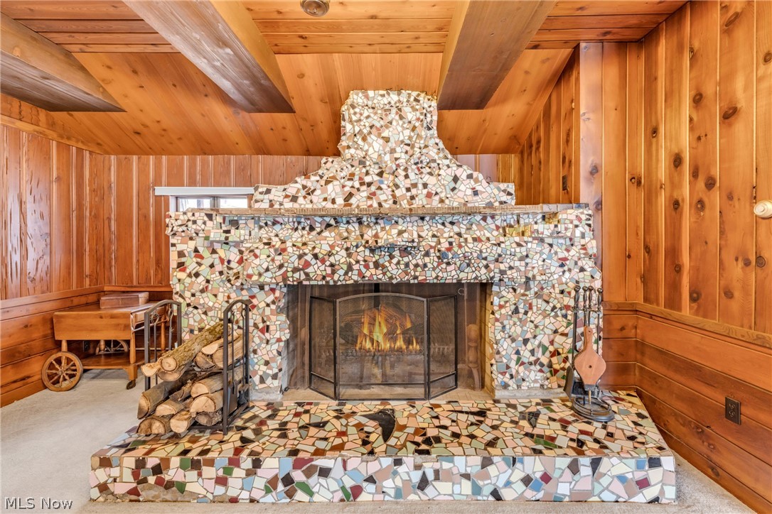 22791 Harms Road Euclid, OH 44143 - Photo 22 of 39 Detailed view of wood walls, carpet flooring, a tiled fireplace, and a wooden ceiling with exposed beams