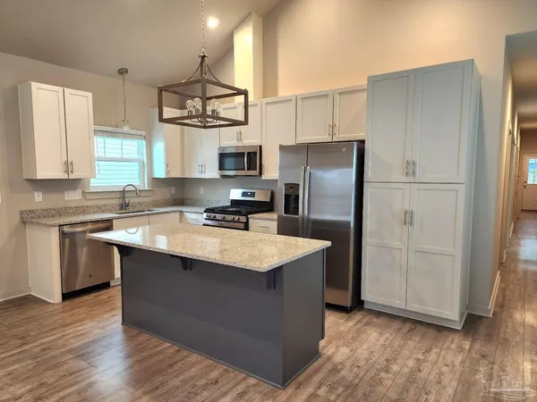 a kitchen with stainless steel appliances granite countertop a refrigerator a sink dishwasher a stove with white cabinets and wooden floor