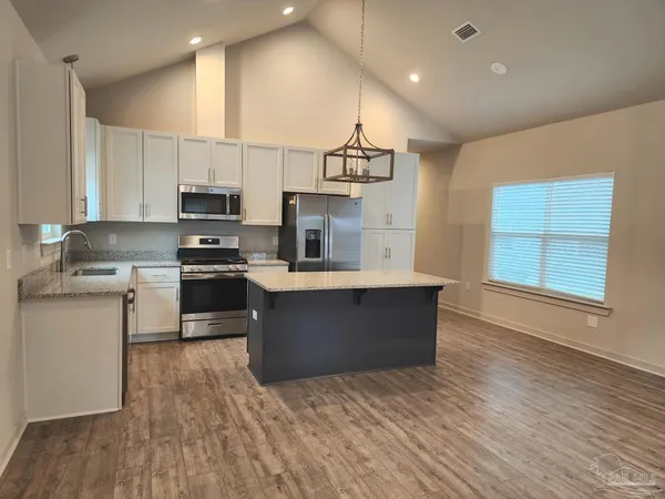 a kitchen with stainless steel appliances kitchen island granite countertop a stove a sink and a refrigerator